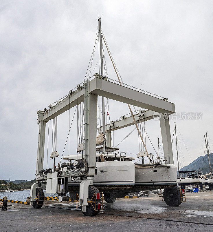 帆船双体船由起重机从干船坞登陆Kaş Marina港进行维修